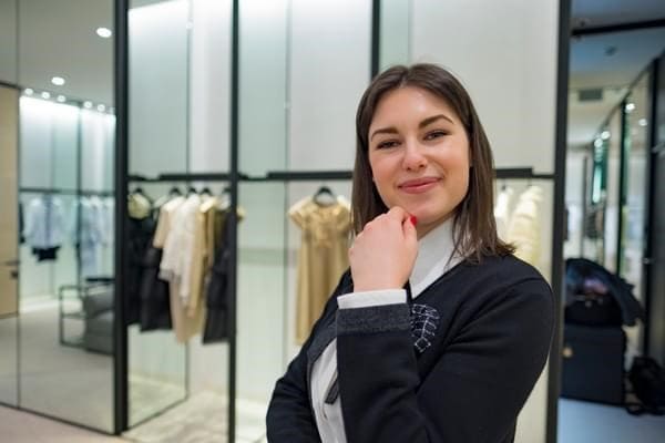 Self-confident B.H.M.S. student in professional uniform standing in front of a luxury store, representing career opportunities after graduation.
