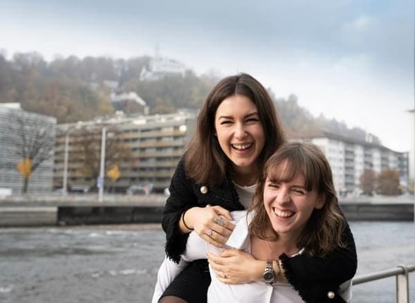 Two cheerful B.H.M.S. students embrace on the shore of Lake Lucerne, symbolizing community and quality leisure time.